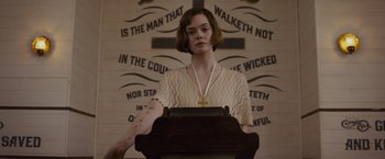 Movie still from “Live by Night” (2016), directed by Ben Affleck – A woman standing at a podium in front of a cross; Medium shot, Low angle