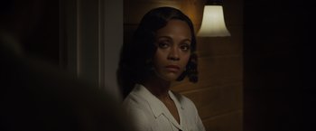 Movie still from “Live by Night” (2016), directed by Ben Affleck – A woman in a white shirt is standing by a wall; Close Up shot, Over the shoulder angle