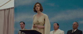 Movie still from “Live by Night” (2016), directed by Ben Affleck – A woman standing in front of two men in front of a podium; Medium shot, Low angle