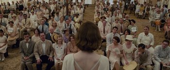 Movie still from “Live by Night” (2016), directed by Ben Affleck – A crowd of people sitting in front of a woman in a white dress; Wide shot, High angle