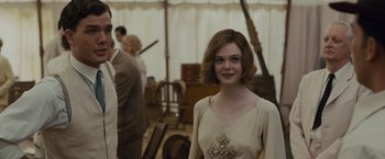 Movie still from “Live by Night” (2016), directed by Ben Affleck – A woman in a beige dress standing in a room; Medium shot, Over the shoulder angle