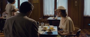 Movie still from “Live by Night” (2016), directed by Ben Affleck – Two people sitting at a table in front of a cup of coffee; Medium shot, Over the shoulder angle