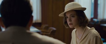 Movie still from “Live by Night” (2016), directed by Ben Affleck – A young woman wearing a hat sitting in front of a man; Close Up shot, Over the shoulder angle