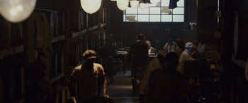 Movie still from “Live by Night” (2016), directed by Ben Affleck – A group of people walking in a dark room; Wide shot, Over the shoulder angle