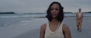 Movie still from “Live by Night” (2016), directed by Ben Affleck – A woman standing on the beach wearing a white tank top; Close Up shot, Over the shoulder angle