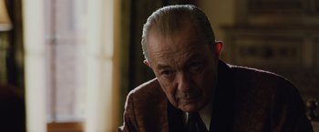 Movie still from “Live by Night” (2016), directed by Ben Affleck – An older man in a suit and tie looking at the camera; Close Up shot, Low angle