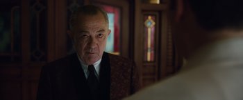 Movie still from “Live by Night” (2016), directed by Ben Affleck – An older man wearing a suit and tie in front of a mirror; Close Up shot, Over the shoulder angle