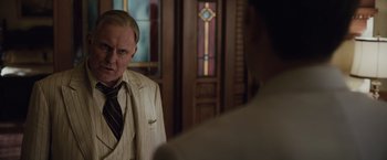 Movie still from “Live by Night” (2016), directed by Ben Affleck – A man wearing a suit and tie standing next to another man in a suit; Close Up shot, Over the shoulder angle