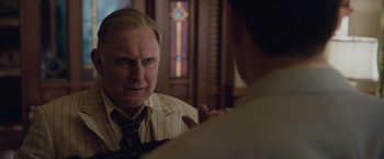 Movie still from “Live by Night” (2016), directed by Ben Affleck – An older man wearing a suit and a tie talking to a younger man; Close Up shot, Over the shoulder angle