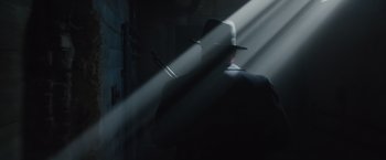 Movie still from “Live by Night” (2016), directed by Ben Affleck – A man wearing a hat standing in a room with light shining on him; Medium shot, Low angle