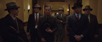 Movie still from “Live by Night” (2016), directed by Ben Affleck – A group of men in suits and hats in a hallway; Medium shot, Low angle
