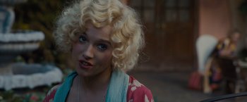 Movie still from “Live by Night” (2016), directed by Ben Affleck – A woman with blonde hair wearing a pink and blue dress; Close Up shot, Over the shoulder angle