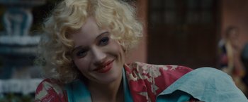 Movie still from “Live by Night” (2016), directed by Ben Affleck – A woman with blonde hair wearing a pink and blue dress; Close Up shot, High angle