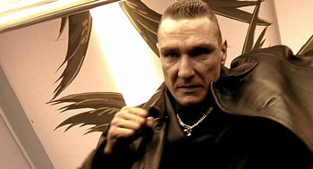 Movie still from “Lock, Stock and Two Smoking Barrels” (1998), directed by Guy Ritchie – A man holding an umbrella in a room; Close Up shot, Low angle