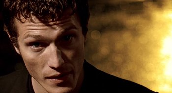Movie still from “Lock, Stock and Two Smoking Barrels” (1998), directed by Guy Ritchie – A man's face in front of blurry lights; Close Up shot, Low angle