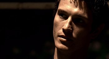 Movie still from “Lock, Stock and Two Smoking Barrels” (1998), directed by Guy Ritchie – A young man's face in the dark; Close Up shot, Low angle
