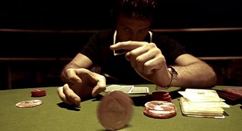 Movie still from “Lock, Stock and Two Smoking Barrels” (1998), directed by Guy Ritchie – A man sitting at a green table with cards in front of him; Extreme Close Up shot, High angle