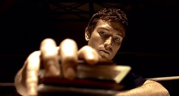 Movie still from “Lock, Stock and Two Smoking Barrels” (1998), directed by Guy Ritchie – A person holding a book in his hand; Close Up shot, Low angle