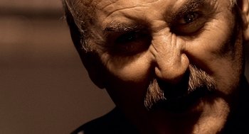 Movie still from “Lock, Stock and Two Smoking Barrels” (1998), directed by Guy Ritchie – An old man with a mustache and a beard; Extreme Close Up shot, Low angle