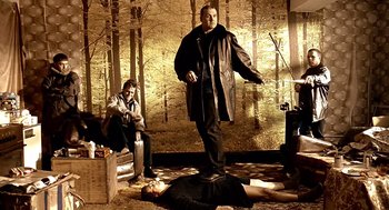 Movie still from “Lock, Stock and Two Smoking Barrels” (1998), directed by Guy Ritchie – A man standing next to a dead body in a forest; Wide shot, Low angle
