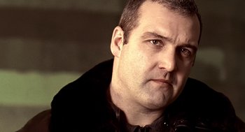 Movie still from “Lock, Stock and Two Smoking Barrels” (1998), directed by Guy Ritchie – A person wearing a black jacket; Close Up shot, Low angle