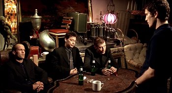 Movie still from “Lock, Stock and Two Smoking Barrels” (1998), directed by Guy Ritchie – A group of men sitting at a table drinking beer; Medium shot, High angle