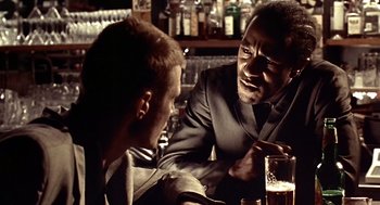 Movie still from “Lock, Stock and Two Smoking Barrels” (1998), directed by Guy Ritchie – Two men are talking at a bar with a beer; Close Up shot, Over the shoulder angle