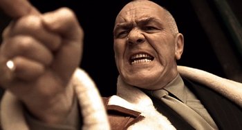 Movie still from “Lock, Stock and Two Smoking Barrels” (1998), directed by Guy Ritchie – A man with a shaved head and bald head is wearing a suit and tie; Close Up shot, Low angle