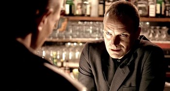 Movie still from “Lock, Stock and Two Smoking Barrels” (1998), directed by Guy Ritchie – A man sitting at a table talking to another man; Close Up shot, Over the shoulder angle