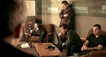 Movie still from “Lock, Stock and Two Smoking Barrels” (1998), directed by Guy Ritchie – A group of men sitting around a coffee table in a living room; Wide shot, High angle