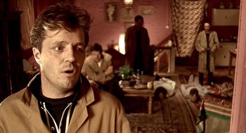 Movie still from “Lock, Stock and Two Smoking Barrels” (1998), directed by Guy Ritchie – A group of people sitting in a living room; Close Up shot, Over the shoulder angle