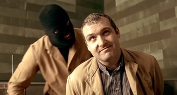 Movie still from “Lock, Stock and Two Smoking Barrels” (1998), directed by Guy Ritchie – A man in a brown jacket and a man in a balaclava; Close Up shot, Over the shoulder angle