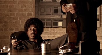 Movie still from “Lock, Stock and Two Smoking Barrels” (1998), directed by Guy Ritchie – A man sitting at a table with a cell phone; Medium shot, Low angle