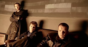 Movie still from “Lock, Stock and Two Smoking Barrels” (1998), directed by Guy Ritchie – A couple of men sitting next to each other on a couch; Medium shot, Low angle