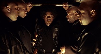 Movie still from “Lock, Stock and Two Smoking Barrels” (1998), directed by Guy Ritchie – A group of men standing next to each other holding guns; Medium shot, Low angle