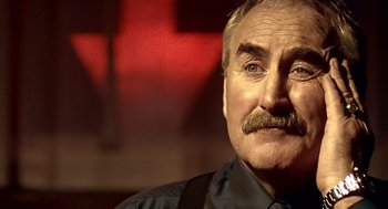 Movie still from “Lock, Stock and Two Smoking Barrels” (1998), directed by Guy Ritchie – An older man with a mustache is looking at the camera; Close Up shot, Low angle