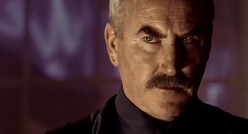 Movie still from “Lock, Stock and Two Smoking Barrels” (1998), directed by Guy Ritchie – An older man with a mustache and a goatee stares into the camera; Close Up shot, Low angle