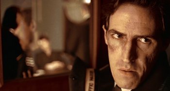 Movie still from “Lock, Stock and Two Smoking Barrels” (1998), directed by Guy Ritchie – A person wearing a suit and tie; Close Up shot, Low angle