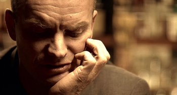 Movie still from “Lock, Stock and Two Smoking Barrels” (1998), directed by Guy Ritchie – A bald man is holding his face in his hand; Extreme Close Up shot, Low angle