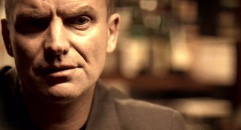 Movie still from “Lock, Stock and Two Smoking Barrels” (1998), directed by Guy Ritchie – A man's face in front of a blurry background; Close Up shot, Low angle