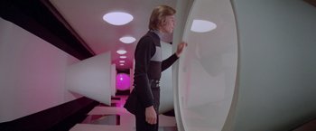 Movie still from “Logan's Run” (1976), directed by Michael Anderson – A man standing in front of a wall in a room; Medium shot, Low angle