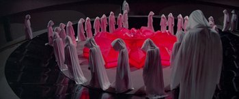 Movie still from “Logan's Run” (1976), directed by Michael Anderson – A group of people dressed in white standing in front of a red circle; Extreme Wide shot, High angle