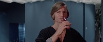 Movie still from “Logan's Run” (1976), directed by Michael Anderson – A man with long hair is holding a glass of wine; Close Up shot, Low angle