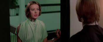 Movie still from “Logan's Run” (1976), directed by Michael Anderson – A woman wearing a green shirt with a cross around her neck; Close Up shot, Over the shoulder angle