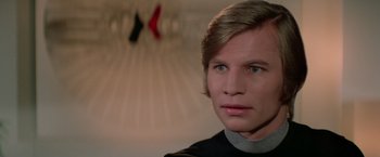 Movie still from “Logan's Run” (1976), directed by Michael Anderson – A man with blonde hair wearing a black shirt; Close Up shot, Low angle