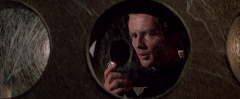 Movie still from “Logan's Run” (1976), directed by Michael Anderson – A man holding a cigarette in front of a round mirror; Close Up shot, Over the shoulder angle