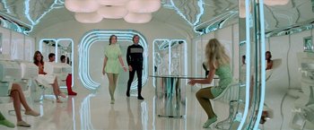Movie still from “Logan's Run” (1976), directed by Michael Anderson – A group of people in a room with a glass table; Wide shot, Over the shoulder angle