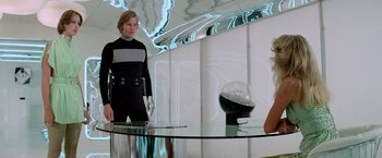 Movie still from “Logan's Run” (1976), directed by Michael Anderson – A woman standing in front of a glass table; Medium shot, Low angle