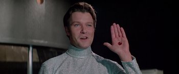 Movie still from “Logan's Run” (1976), directed by Michael Anderson – A man in a silver shirt holding his hand up; Close Up shot, Low angle