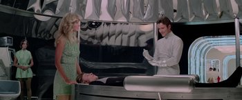 Movie still from “Logan's Run” (1976), directed by Michael Anderson – Two women and a man are standing next to a bed; Medium shot, Low angle